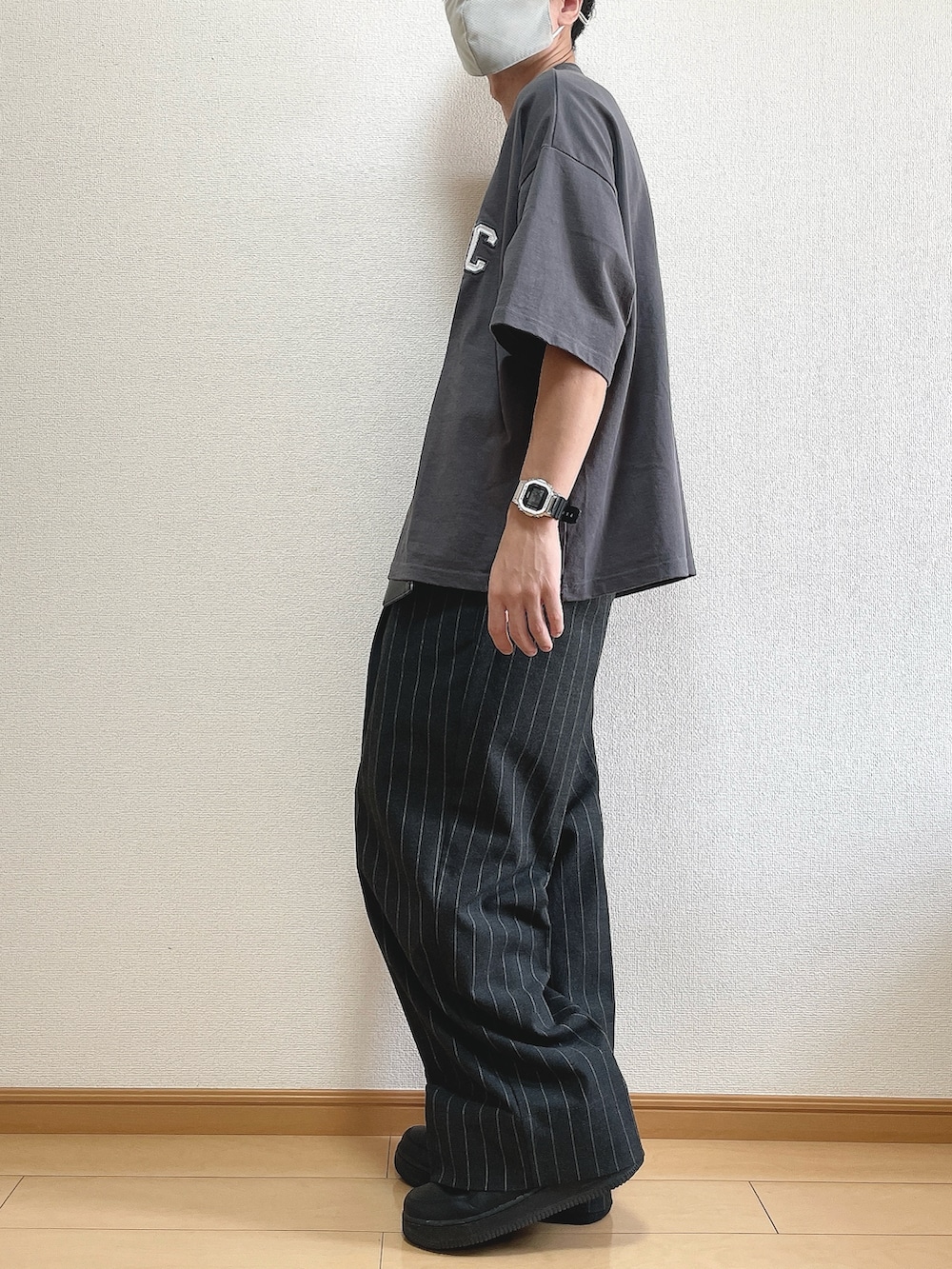 グレー系のTシャツ/カットソー、ブラック系のパンツ、ブラック系のスニーカーを着用したメンズの秋コーディネートの2枚目の写真