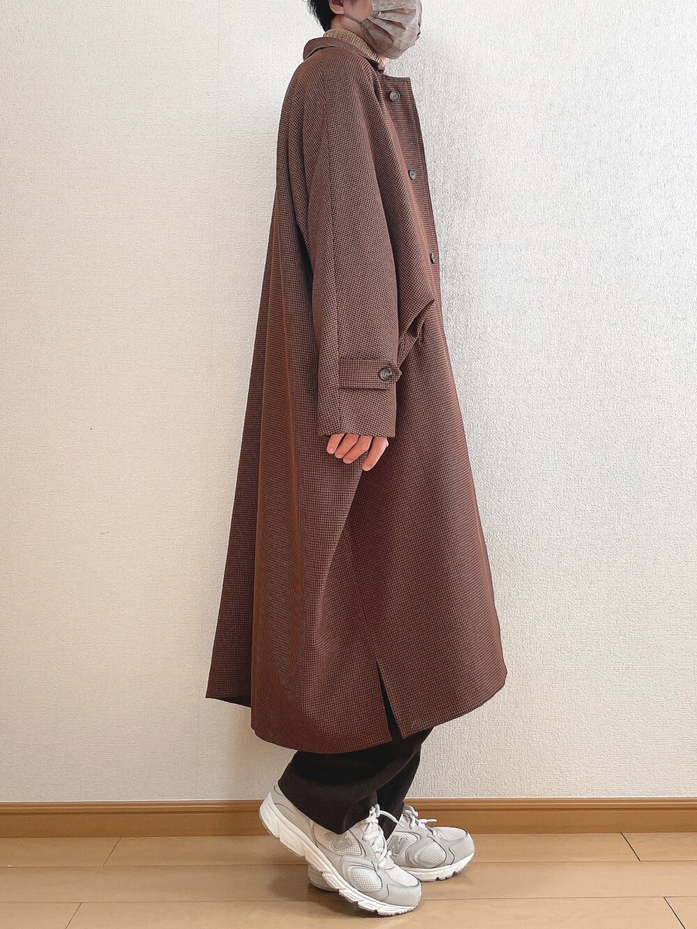 ブラウン系のステンカラーコート、ベージュ系のニット/セーター、ブラウン系のスラックスを着用したメンズの冬コーディネートの2枚目の写真