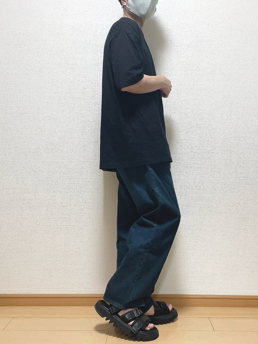 ブラック系のTシャツ/カットソー、ブルー系のデニムパンツ、ブラック系のサンダルを着用したメンズの春コーディネートの2枚目の写真