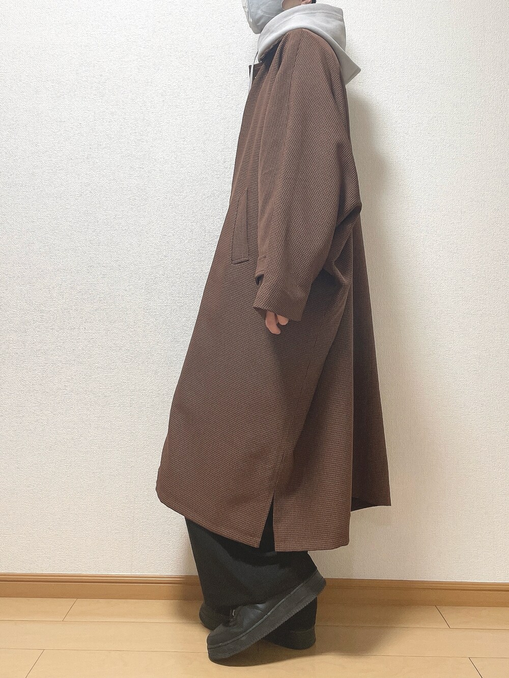 ブラウン系のステンカラーコート、グレー系のパーカー、ブラック系のその他パンツを着用したメンズの冬コーディネートの3枚目の写真