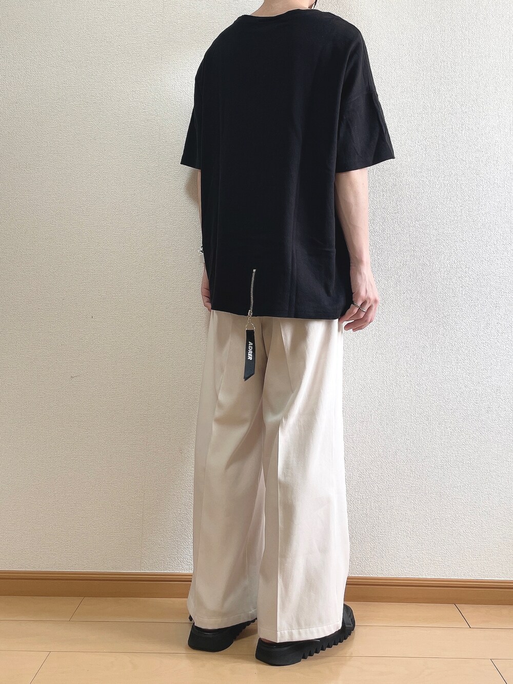 ブラック系のTシャツ/カットソー、ベージュ系のスラックス、ブラック系のサンダルを着用したメンズの夏コーディネートの4枚目の写真