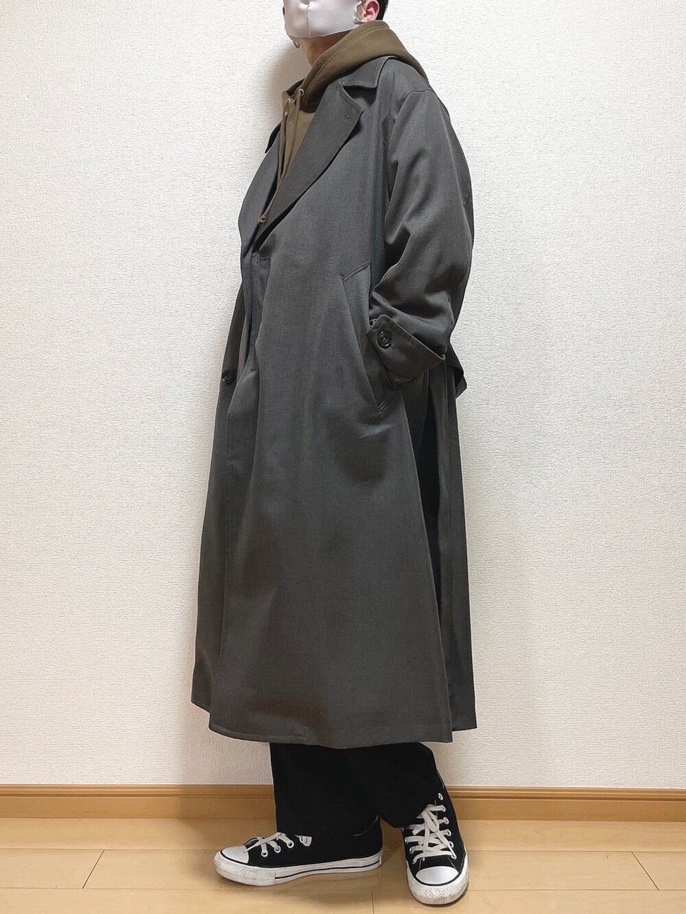 グレー系のトレンチコート、ブラウン系のパーカー、ブラック系のスラックスを着用したメンズの冬コーディネートの2枚目の写真