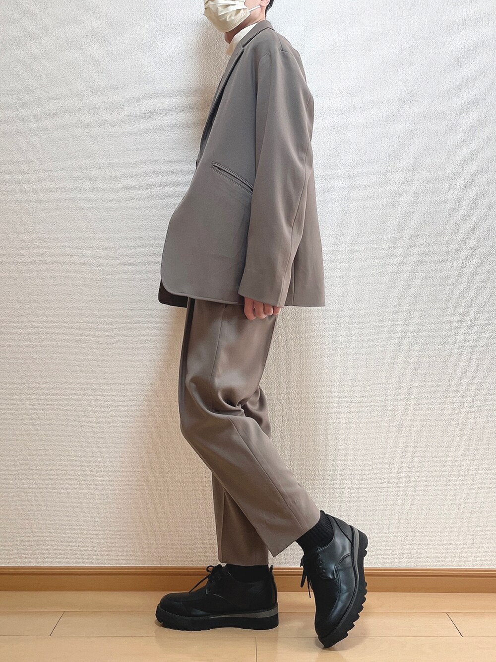 ベージュ系のセットアップ、ホワイト系のTシャツ/カットソー、ブラック系のドレスシューズを着用したメンズの冬コーディネートの3枚目の写真