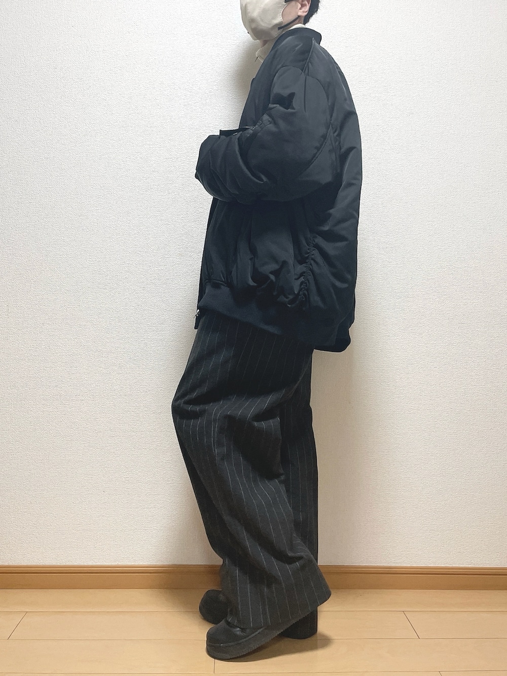 ブラック系のMA-1、ベージュ系のニット/セーター、ブラック系のパンツを着用したメンズの冬コーディネートの3枚目の写真