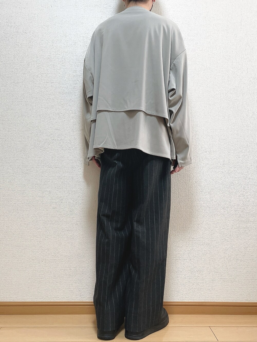 グレー系のブルゾン、ホワイト系のTシャツ/カットソー、ブラック系のパンツを着用したメンズの秋コーディネートの4枚目の写真