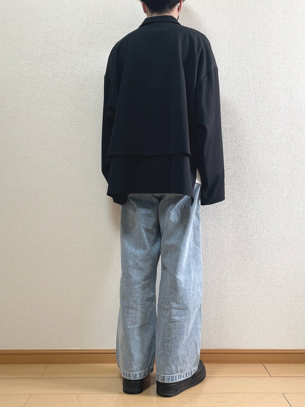 ブラック系のブルゾン、ホワイト系のTシャツ/カットソー、ブルー系のデニムパンツを着用したメンズの春コーディネートの4枚目の写真