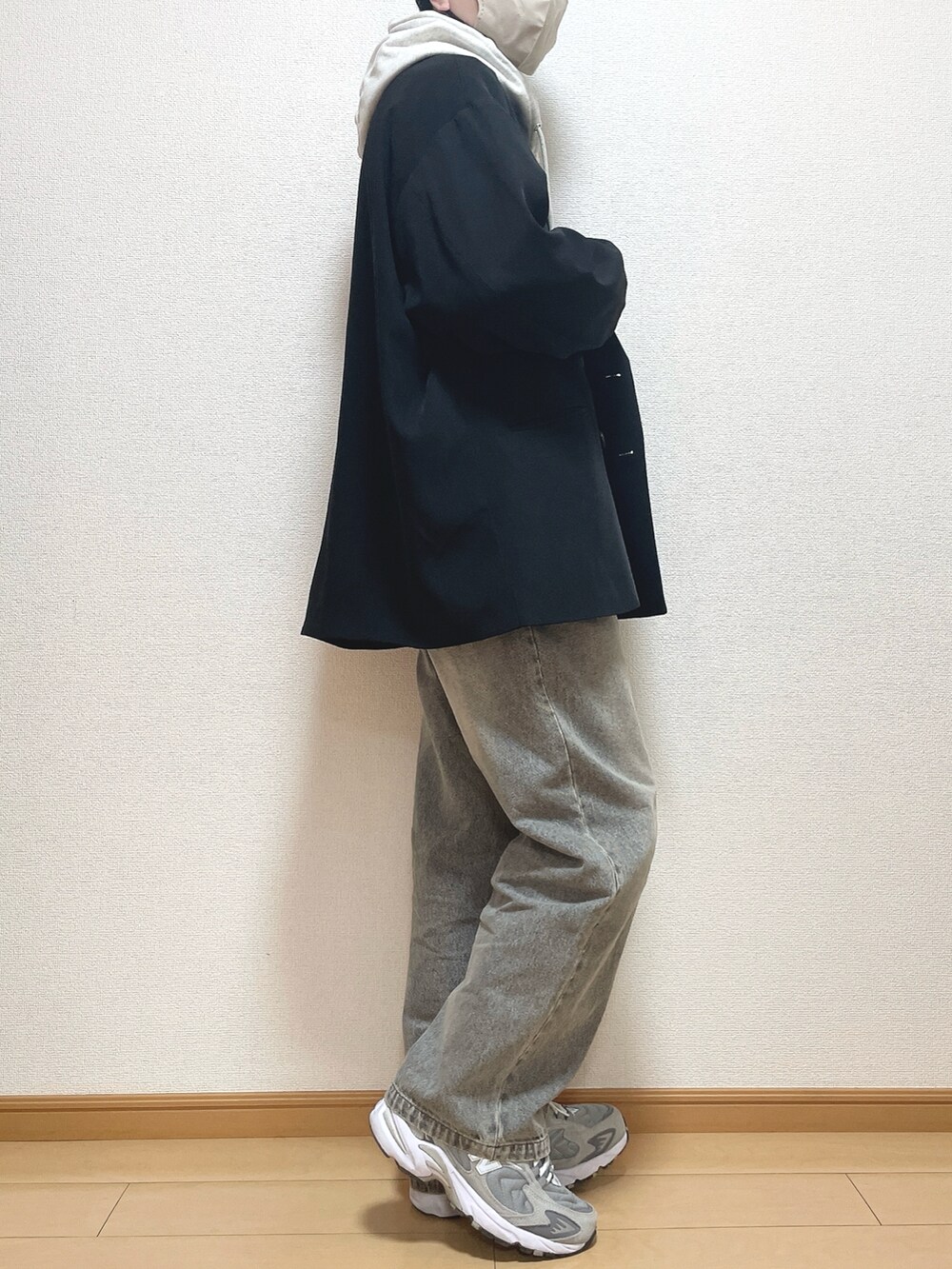 ブラック系のテーラードジャケット、グレー系のパーカー、ブラック系のデニムパンツを着用したメンズの冬コーディネートの2枚目の写真