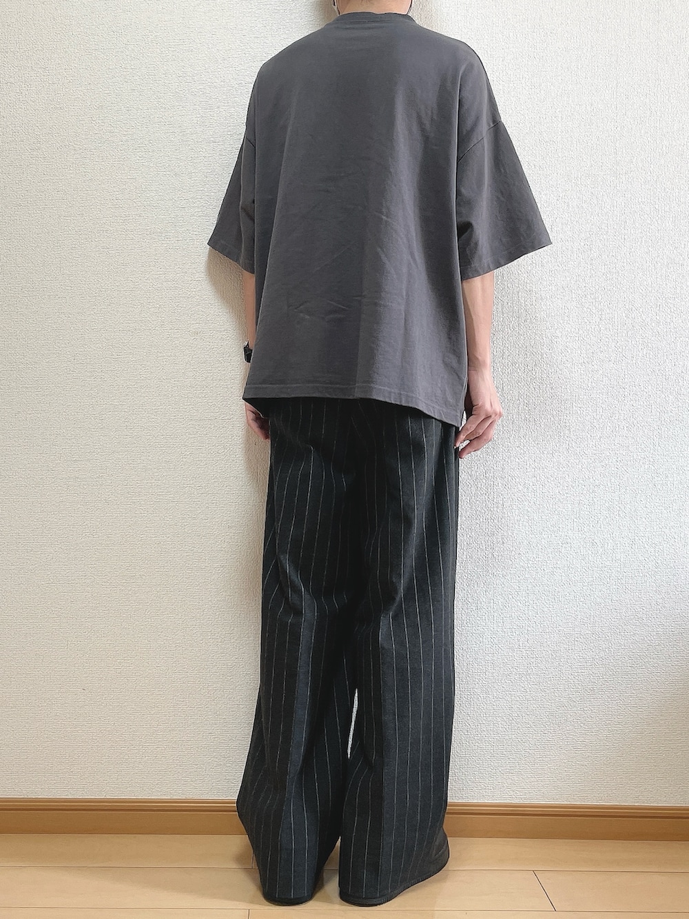 グレー系のTシャツ/カットソー、ブラック系のパンツ、ブラック系のスニーカーを着用したメンズの秋コーディネートの4枚目の写真