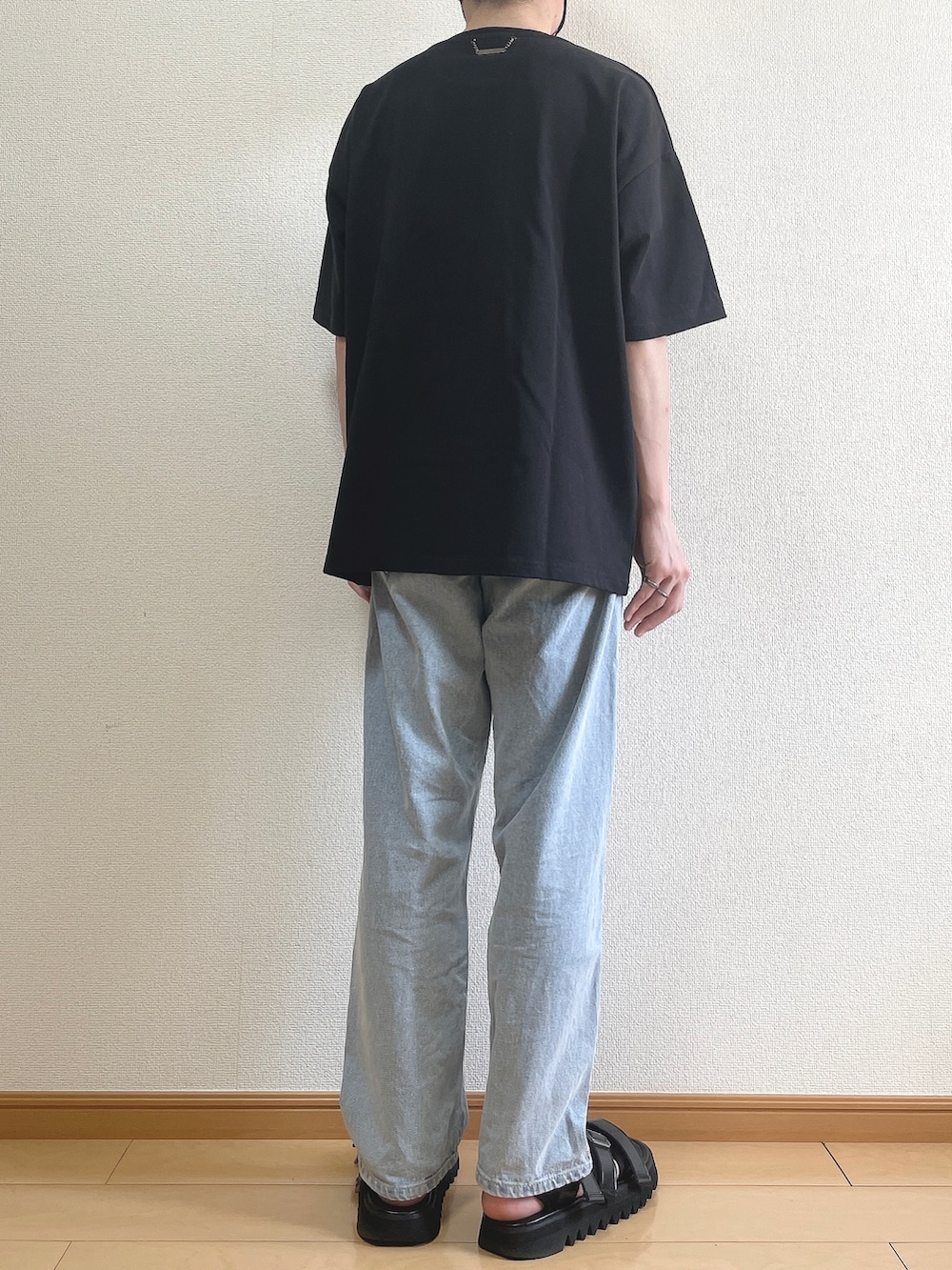 ブラック系のTシャツ/カットソー、ブルー系のデニムパンツ、ブラック系のサンダルを着用したメンズの春コーディネートの4枚目の写真