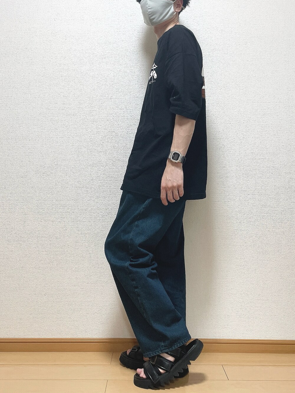 ブラック系のTシャツ/カットソー、ブルー系のデニムパンツ、ブラック系のサンダルを着用したメンズの春コーディネートの3枚目の写真