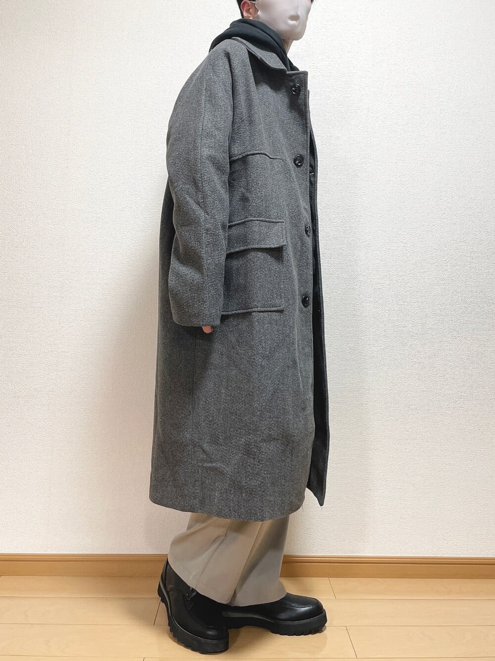 グレー系のステンカラーコート、ブラック系のパーカー、グレー系のその他パンツを着用したメンズの秋コーディネートの3枚目の写真