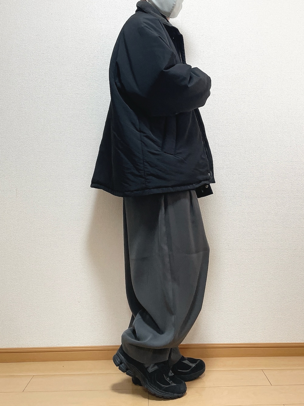 ブラック系のその他アウター、ベージュ系のニット/セーター、グレー系のスラックスを着用したメンズの春コーディネートの2枚目の写真