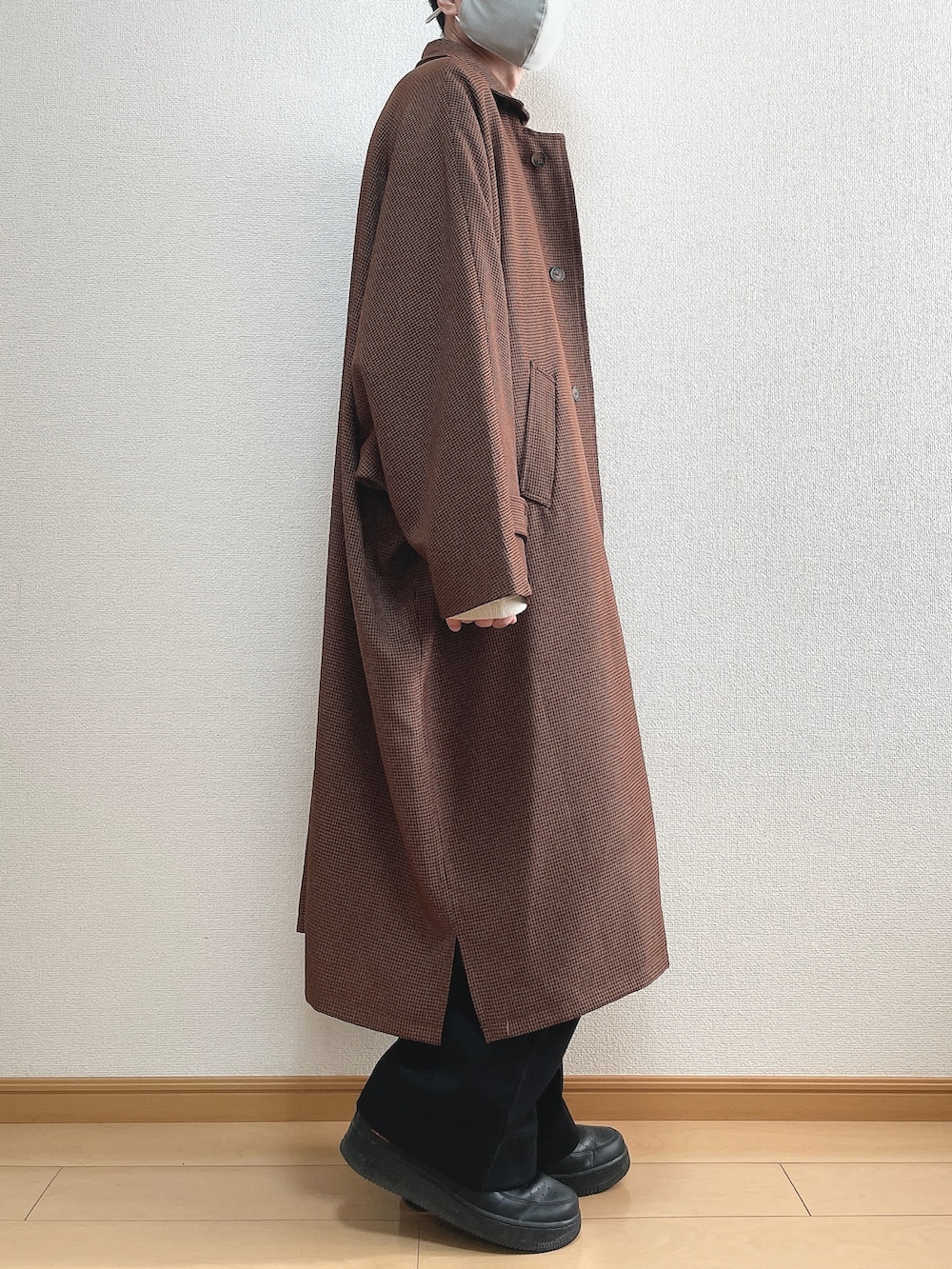 ブラウン系のステンカラーコート、ホワイト系のニット/セーター、ブラック系のスラックスを着用したメンズの冬コーディネートの2枚目の写真