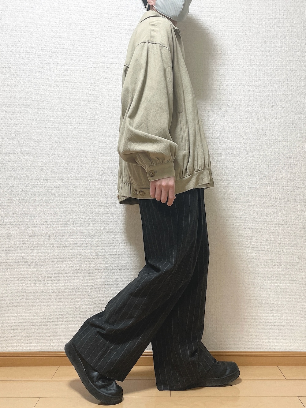 ベージュ系のブルゾン、ホワイト系のTシャツ/カットソー、ブラック系のパンツを着用したメンズの春コーディネートの2枚目の写真