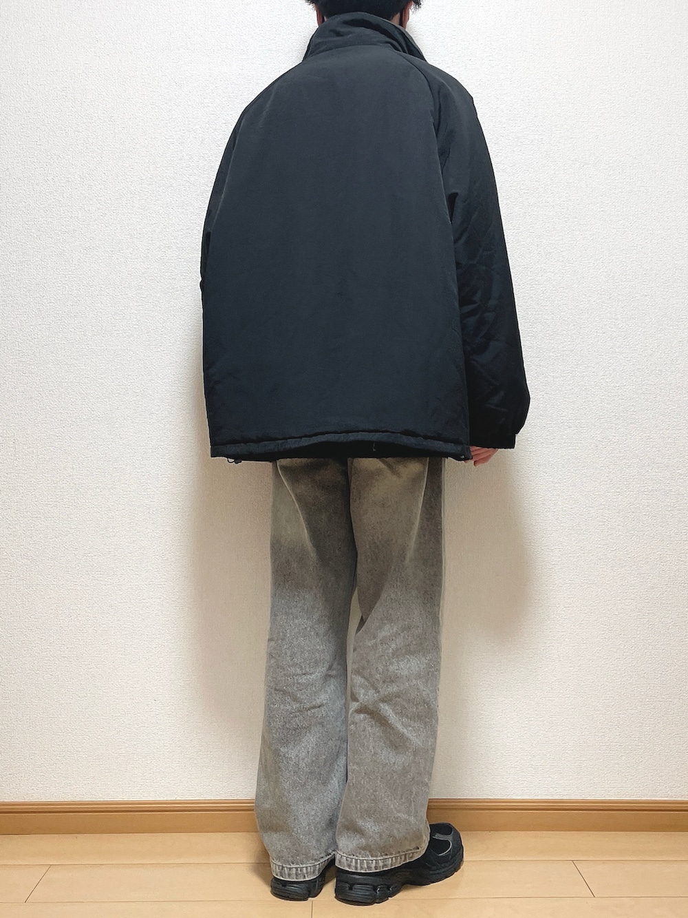 ブラック系のその他アウター、ベージュ系のニット/セーター、ブラック系のデニムパンツを着用したメンズの冬コーディネートの4枚目の写真