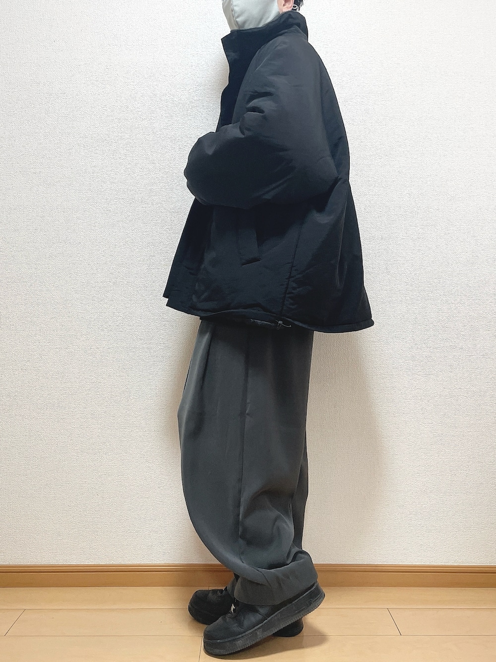 ブラック系のその他アウター、グレー系のニット/セーター、グレー系のスラックスを着用したメンズの冬コーディネートの3枚目の写真