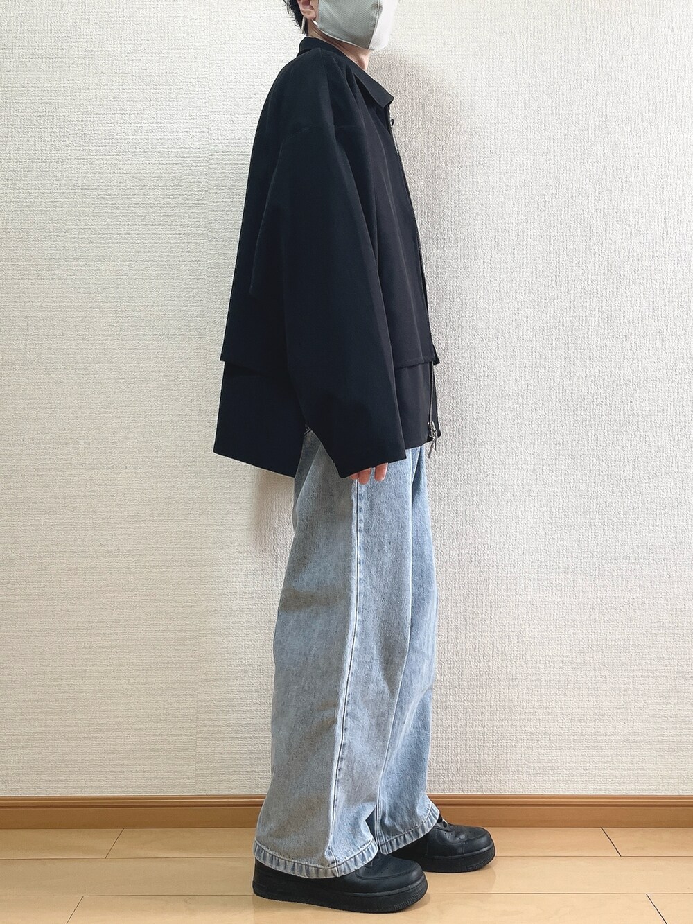 ブラック系のブルゾン、ホワイト系のTシャツ/カットソー、ブルー系のデニムパンツを着用したメンズの春コーディネートの2枚目の写真