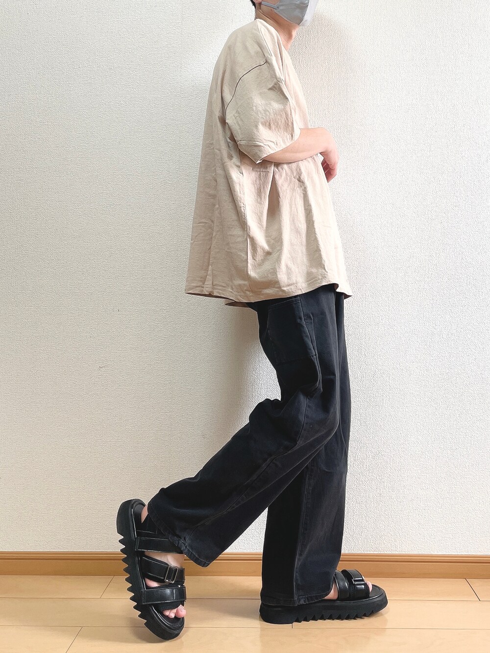 ベージュ系のTシャツ/カットソー、ブラック系のデニムパンツ、ブラック系のサンダルを着用したメンズの夏コーディネートの2枚目の写真