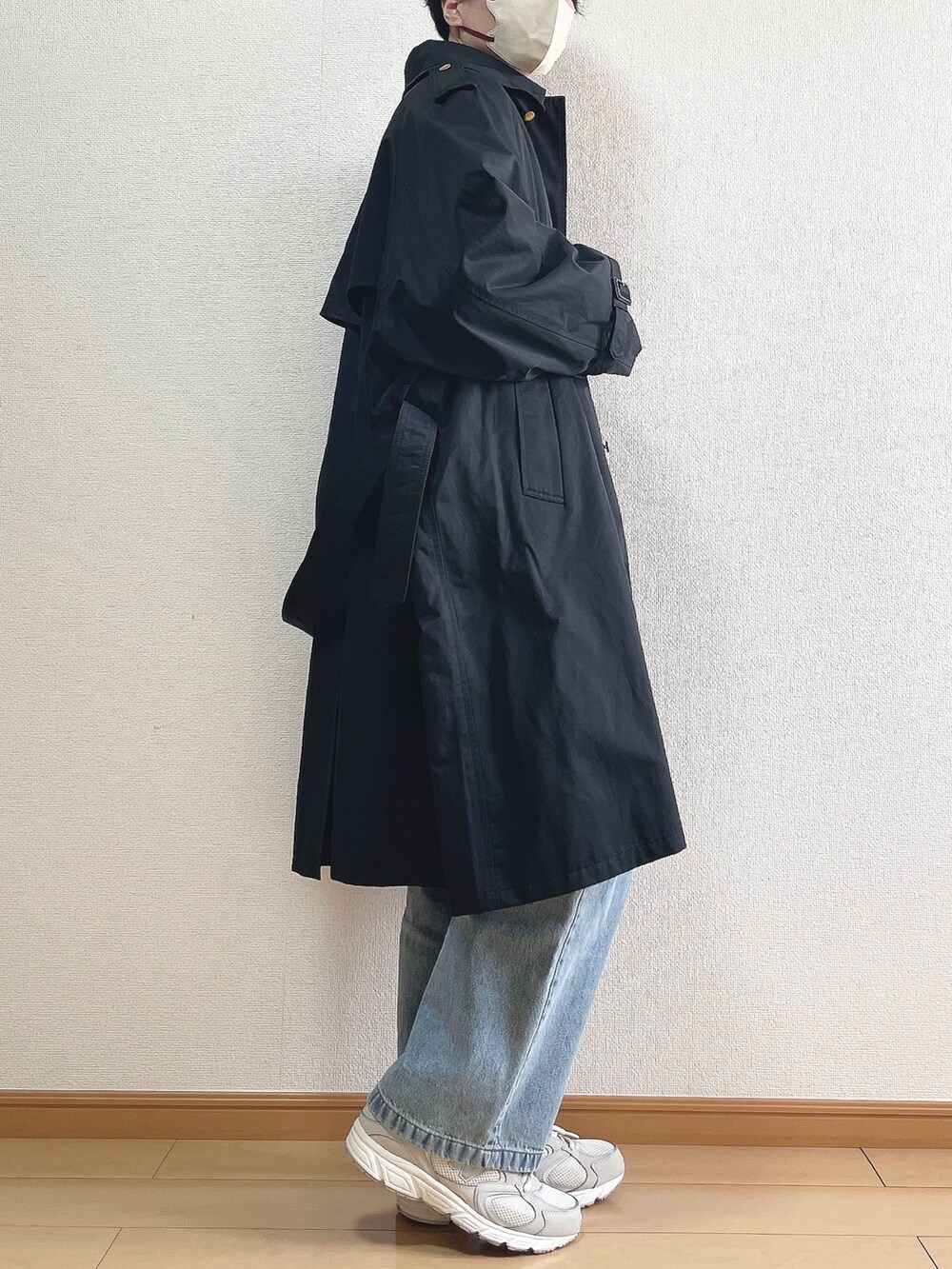 ブラック系のトレンチコート、ベージュ系のニット/セーター、ホワイト系のTシャツ/カットソーを着用したメンズの春コーディネートの2枚目の写真