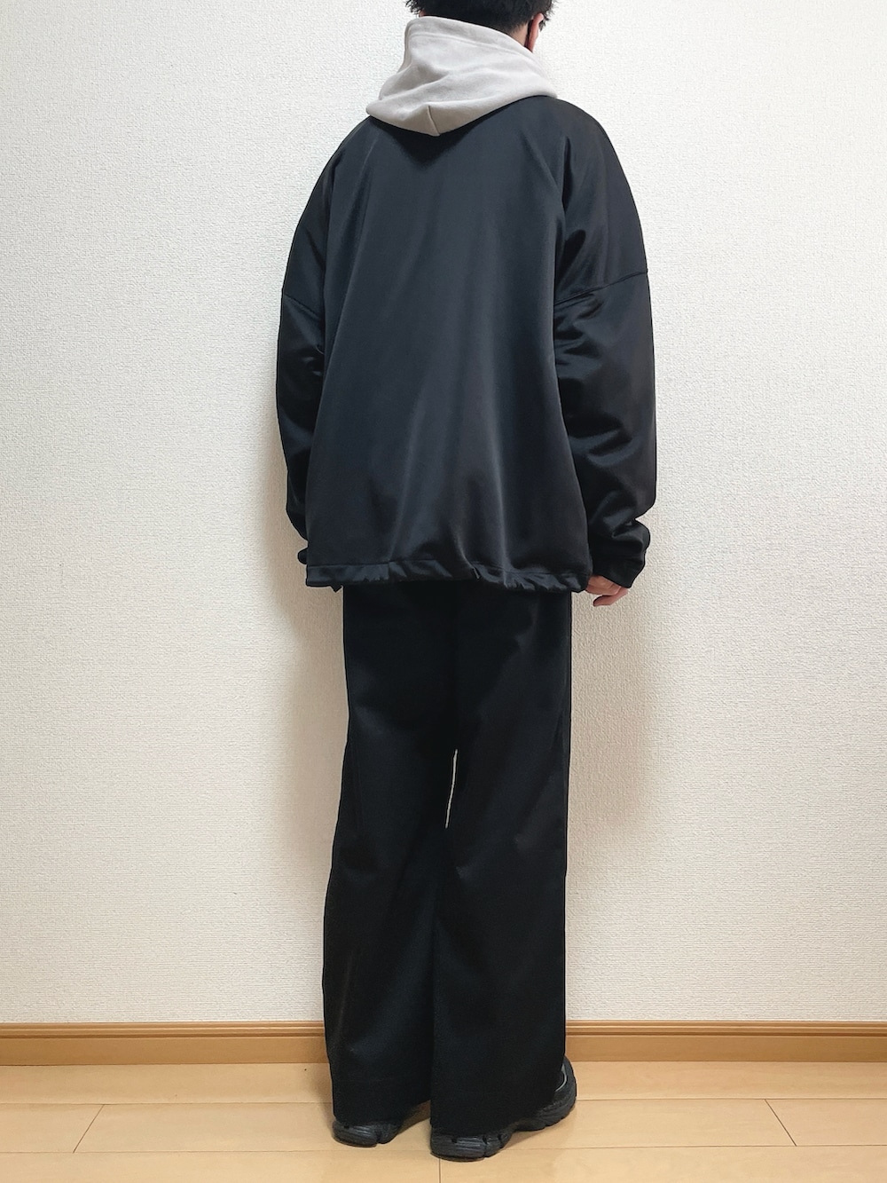 ブラック系のブルゾン、グレー系のパーカー、ブラック系のスラックスを着用したメンズの春コーディネートの4枚目の写真