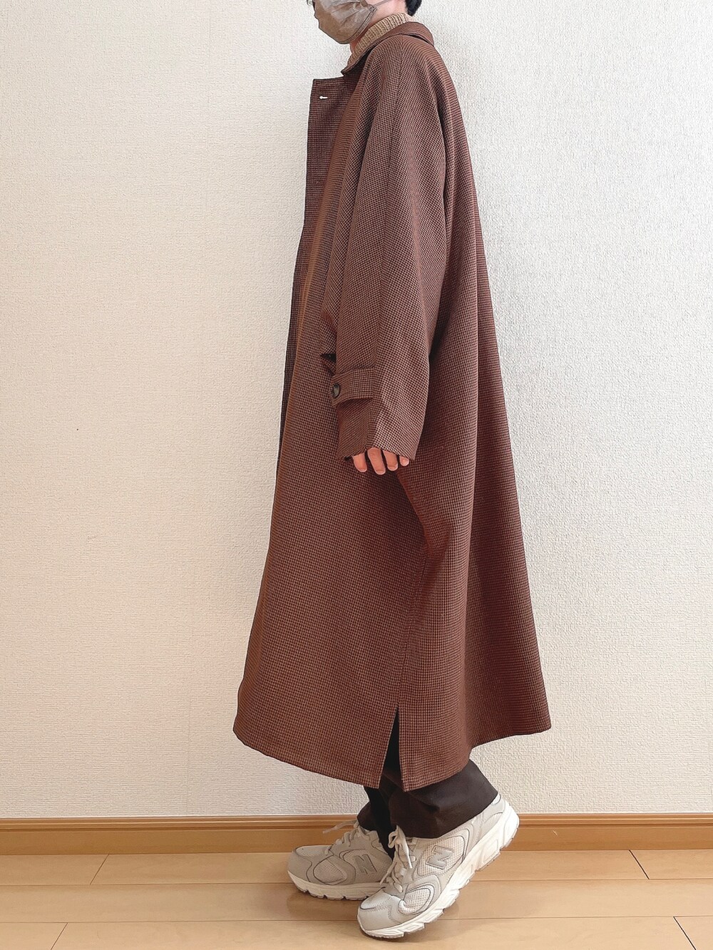 ブラウン系のステンカラーコート、ベージュ系のニット/セーター、ブラウン系のスラックスを着用したメンズの冬コーディネートの3枚目の写真