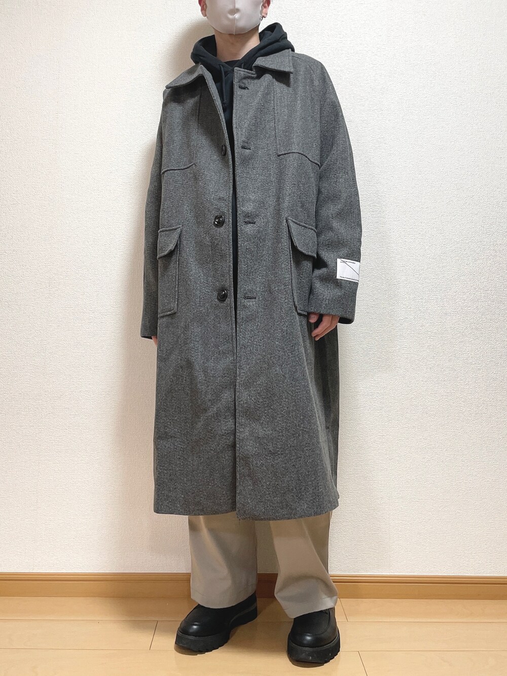 グレー系のステンカラーコート、ブラック系のパーカー、グレー系のその他パンツを着用したメンズの秋コーディネートの2枚目の写真