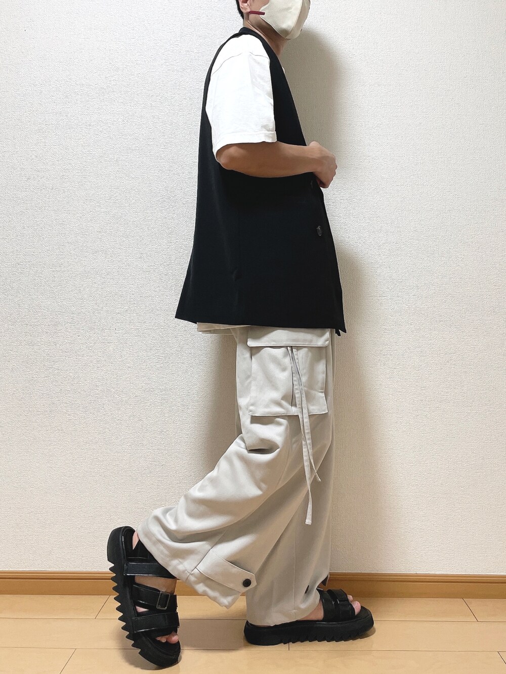 ブラック系のベスト、ホワイト系のTシャツ/カットソー、グレー系のカーゴパンツを着用したメンズの秋コーディネートの2枚目の写真