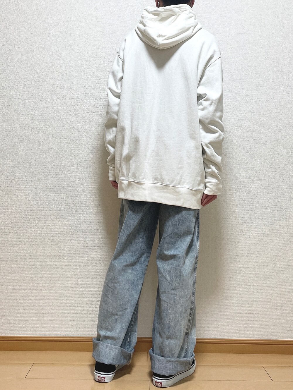 ホワイト系のパーカー、ブルー系のデニムパンツ、ブラック系のスニーカーを着用したメンズの春コーディネートの4枚目の写真