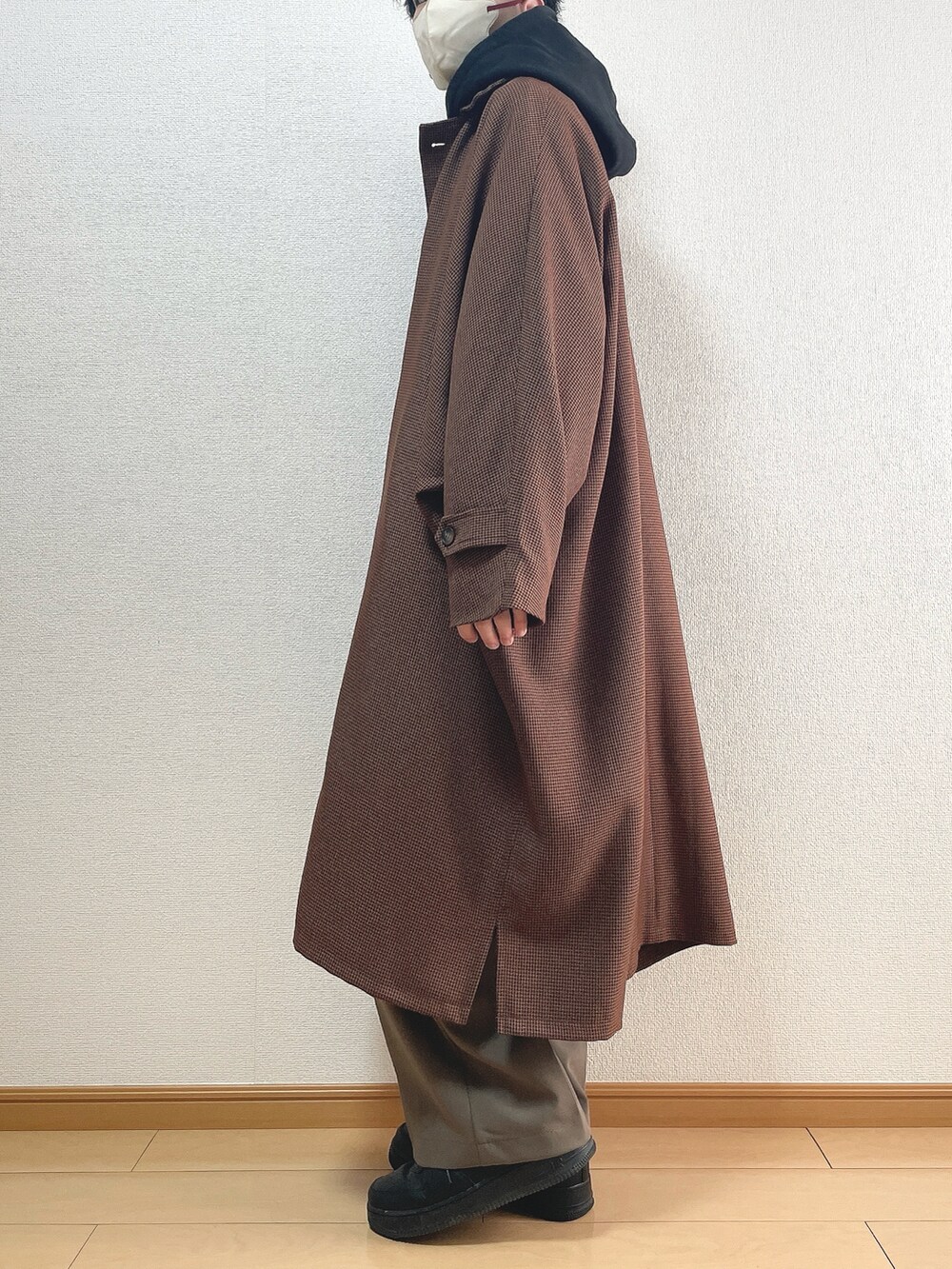 ブラウン系のステンカラーコート、ブラック系のパーカー、ブラウン系のその他パンツを着用したメンズの春コーディネートの3枚目の写真