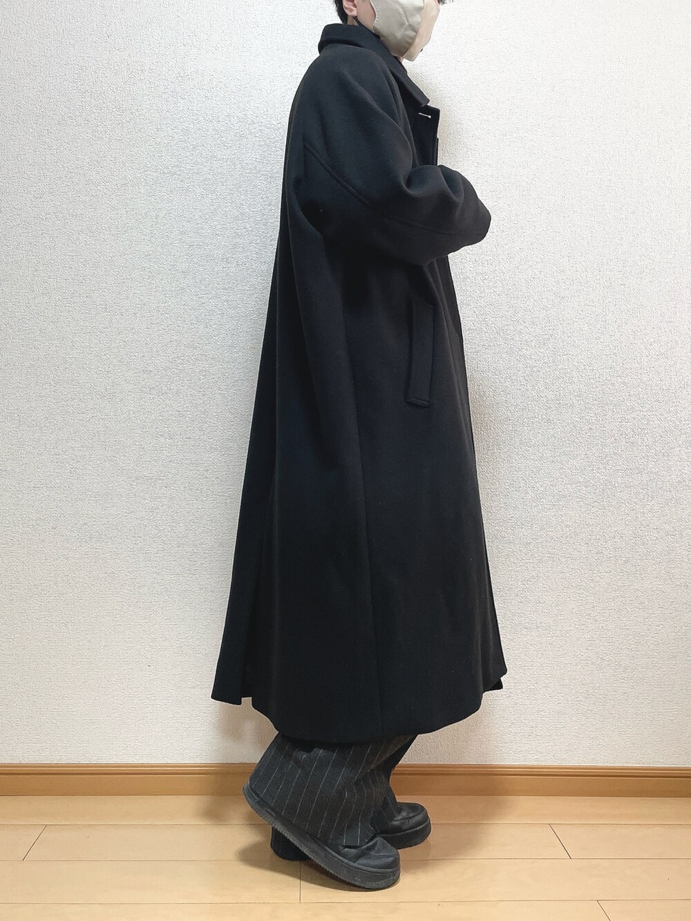 ブラック系のステンカラーコート、ブラック系のニット/セーター、ブラック系のパンツを着用したメンズの冬コーディネートの2枚目の写真