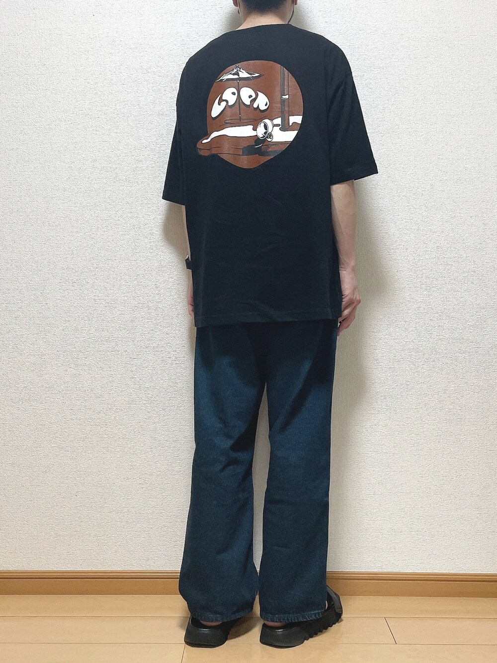 ブラック系のTシャツ/カットソー、ブルー系のデニムパンツ、ブラック系のサンダルを着用したメンズの春コーディネートの4枚目の写真