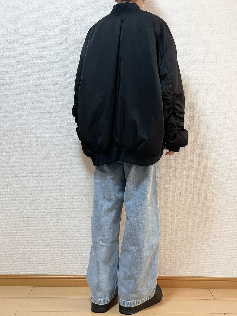 ブラック系のMA-1、ブラック系のスウェット、ブルー系のデニムパンツを着用したメンズの冬コーディネートの4枚目の写真