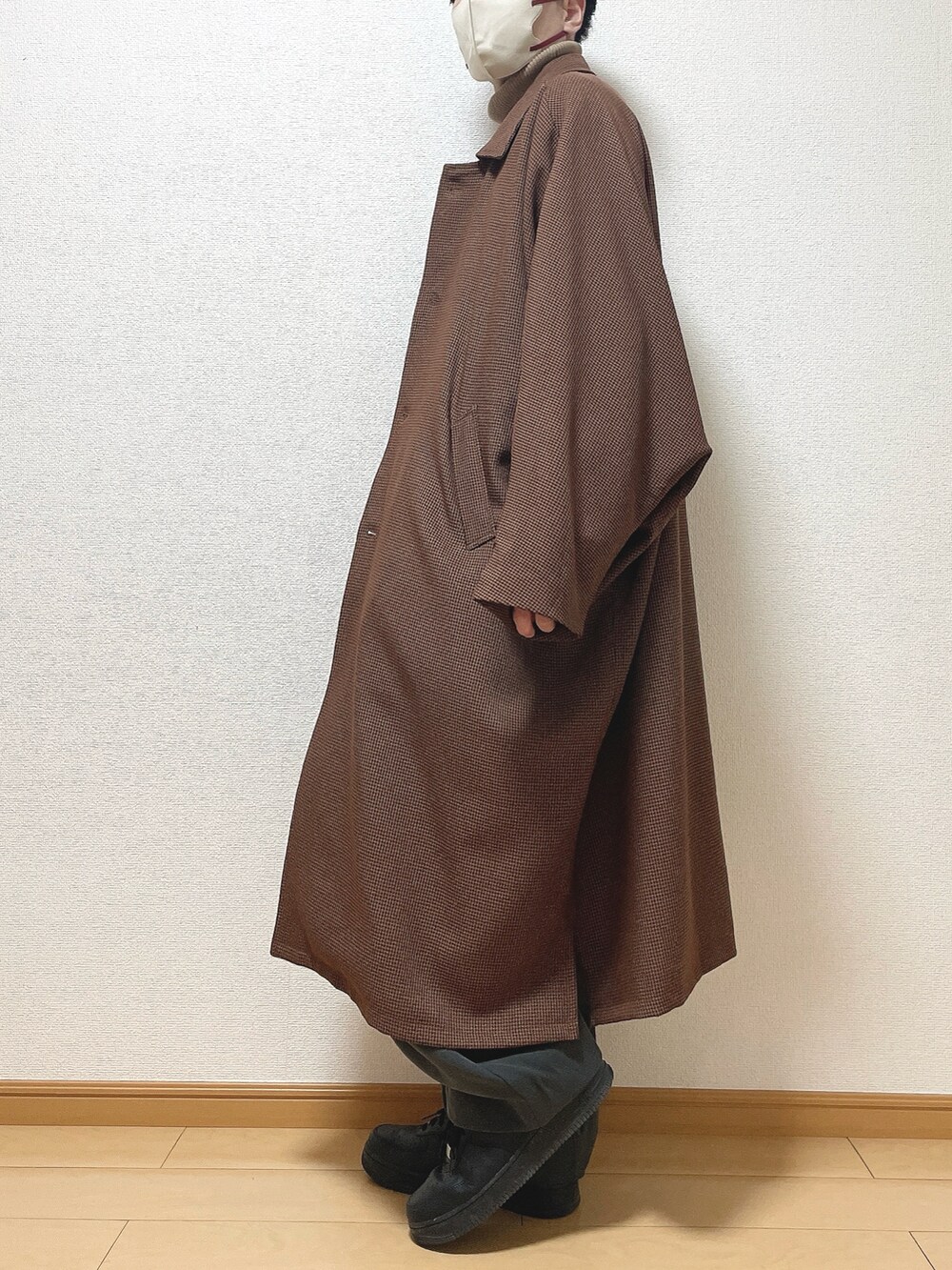 ブラウン系のステンカラーコート、ベージュ系のニット/セーター、グレー系のスラックスを着用したメンズの冬コーディネートの3枚目の写真