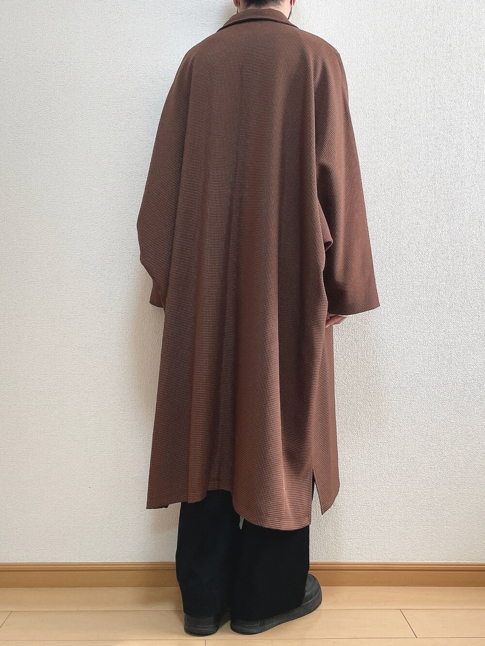 ブラウン系のステンカラーコート、ホワイト系のニット/セーター、ブラック系のスラックスを着用したメンズの冬コーディネートの4枚目の写真