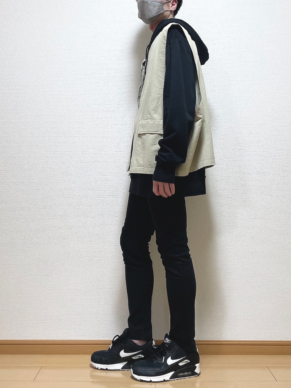 ベージュ系のベスト、ブラック系のパーカー、ブラック系のデニムパンツを着用したメンズの春コーディネートの4枚目の写真