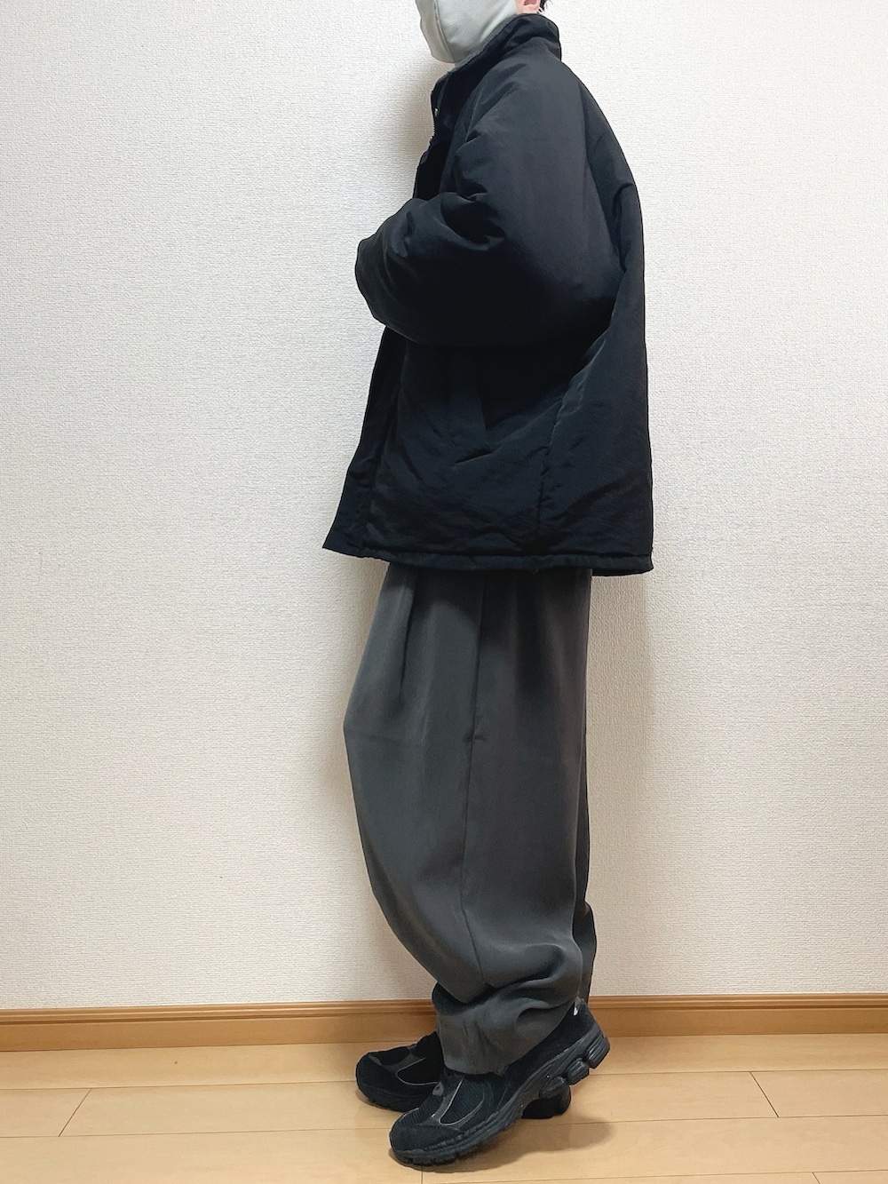 ブラック系のその他アウター、ベージュ系のニット/セーター、グレー系のスラックスを着用したメンズの春コーディネートの3枚目の写真