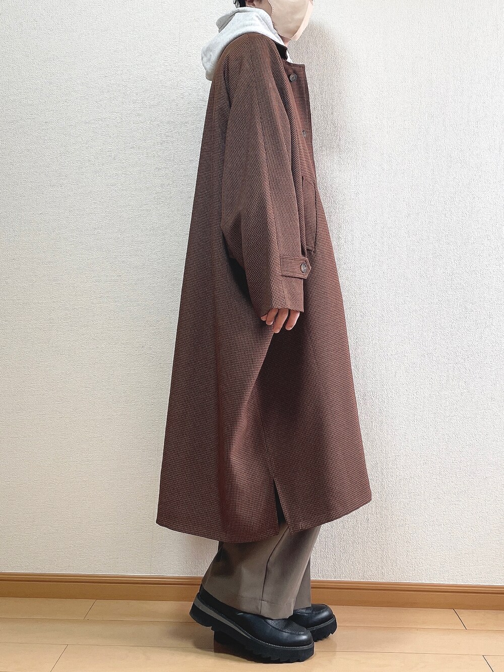 ブラウン系のステンカラーコート、グレー系のパーカー、ブラック系のTシャツ/カットソーを着用したメンズの冬コーディネートの2枚目の写真