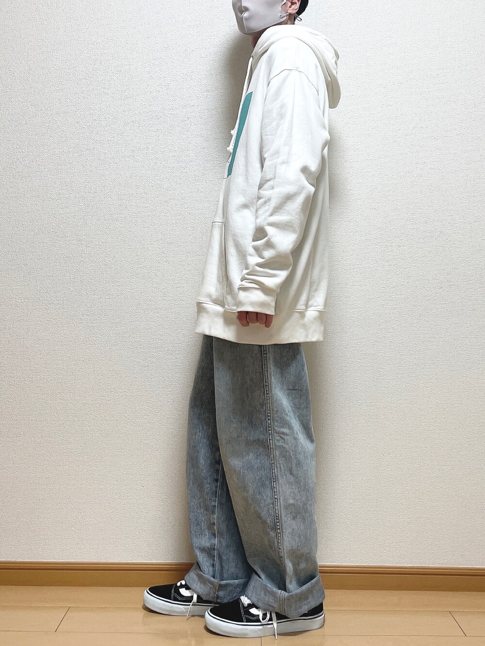 ホワイト系のパーカー、ブルー系のデニムパンツ、ブラック系のスニーカーを着用したメンズの春コーディネートの3枚目の写真