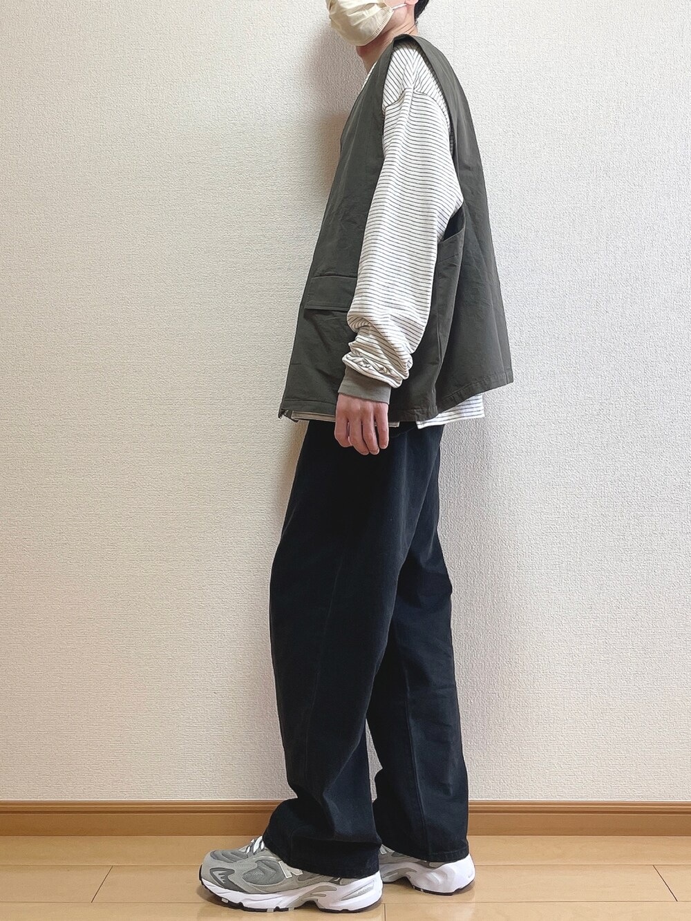 グレー系のベスト、グリーン系のTシャツ/カットソー、ブラック系のデニムパンツを着用したメンズの春コーディネートの2枚目の写真