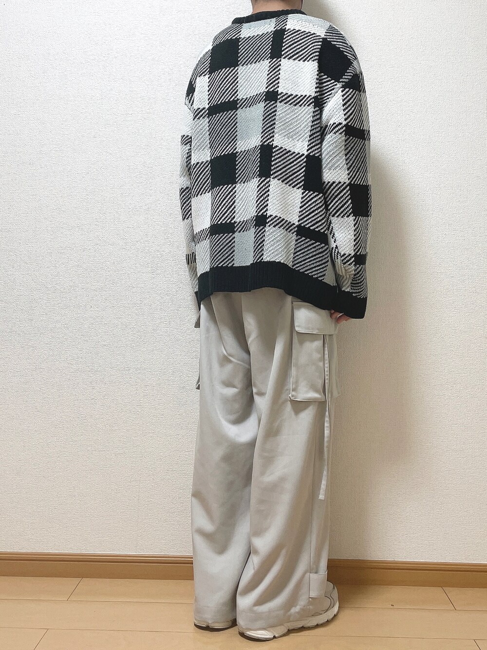 ブラック系のニット/セーター、グレー系のカーゴパンツ、ホワイト系のスニーカーを着用したメンズの秋コーディネートの4枚目の写真