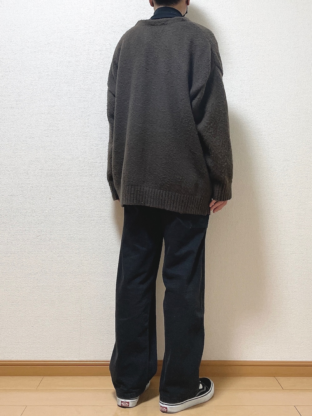 ブラウン系のカーディガン/ボレロ、ブラック系のTシャツ/カットソー、ブラック系のデニムパンツを着用したメンズの冬コーディネートの4枚目の写真