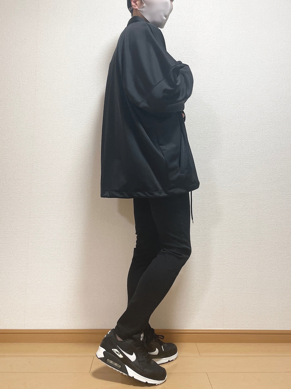 ブラック系のブルゾン、ホワイト系のニット/セーター、ブラック系のデニムパンツを着用したメンズの秋コーディネートの3枚目の写真