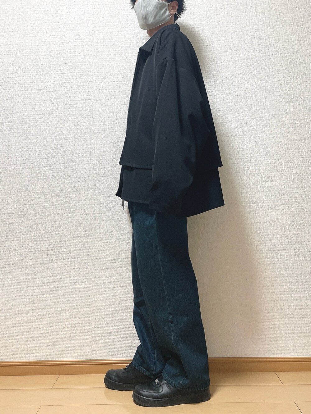 ブラック系のブルゾン、ホワイト系のTシャツ/カットソー、ブルー系のデニムパンツを着用したメンズの春コーディネートの3枚目の写真