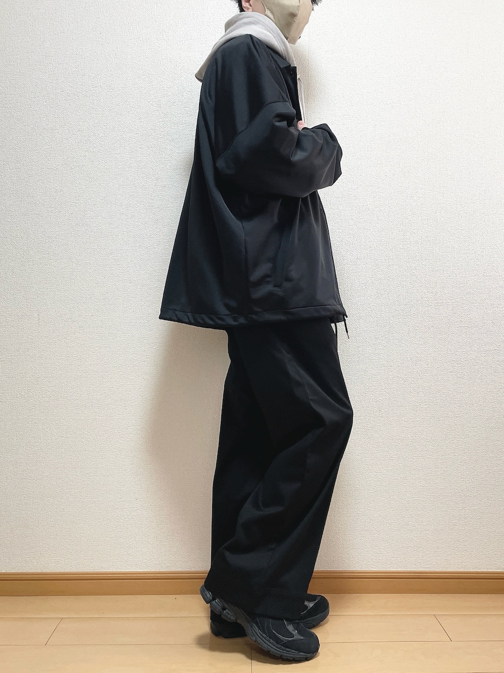 ブラック系のブルゾン、グレー系のパーカー、ブラック系のスラックスを着用したメンズの春コーディネートの2枚目の写真