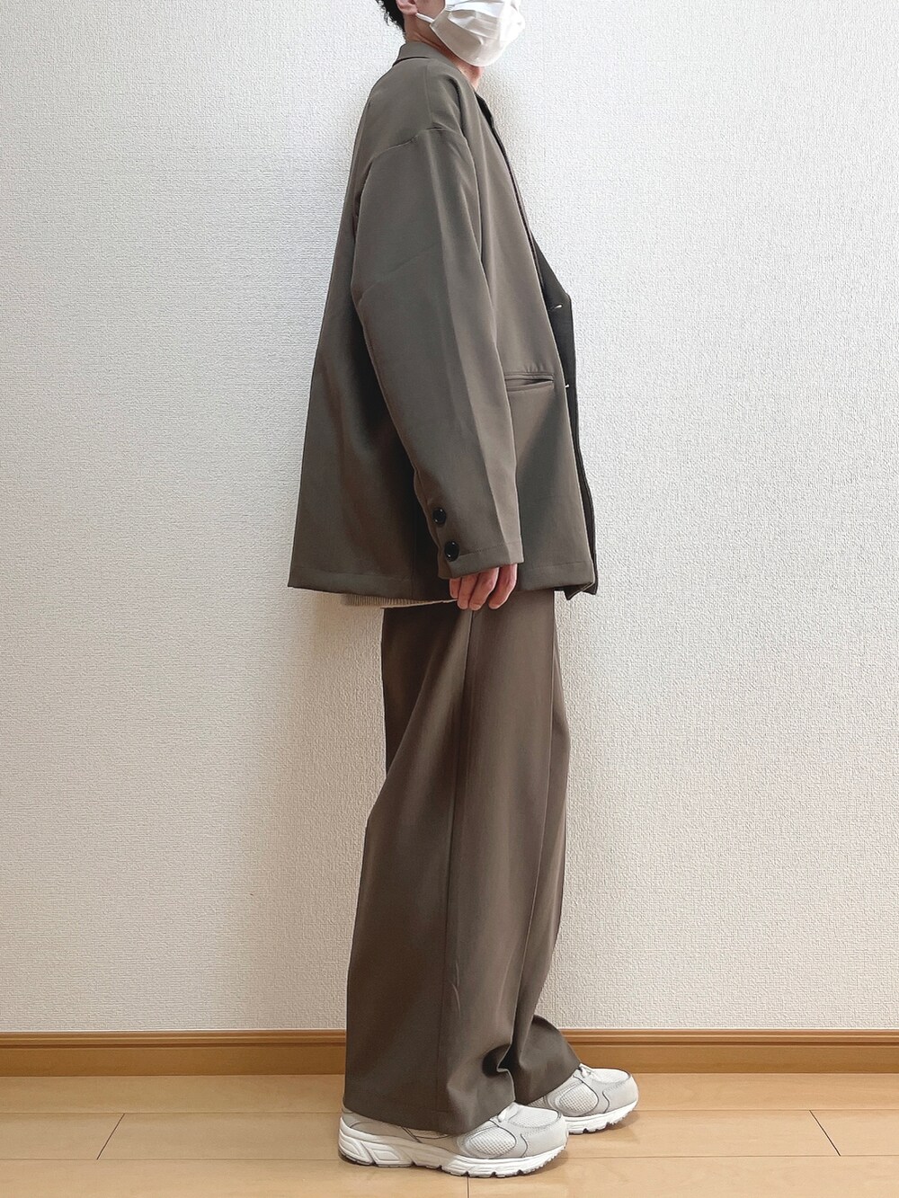 ブラウン系のテーラードジャケット、ベージュ系のニット/セーター、ホワイト系のTシャツ/カットソーを着用したメンズの春コーディネートの2枚目の写真
