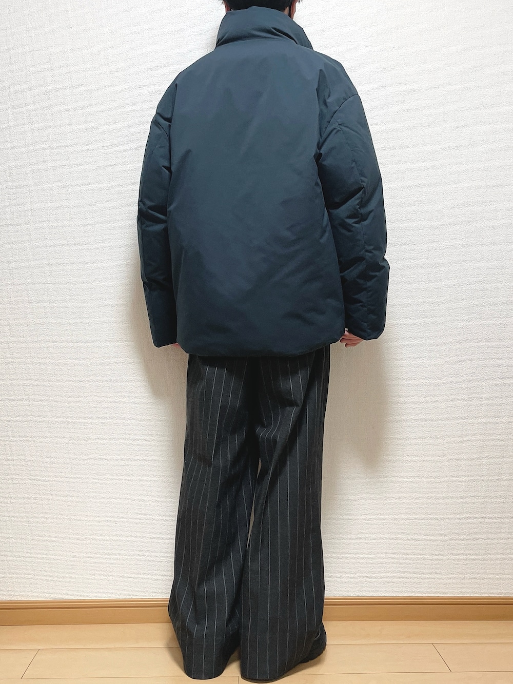 グレー系のダウンジャケット/コート、ベージュ系のニット/セーター、ブラック系のパンツを着用したメンズの冬コーディネートの4枚目の写真