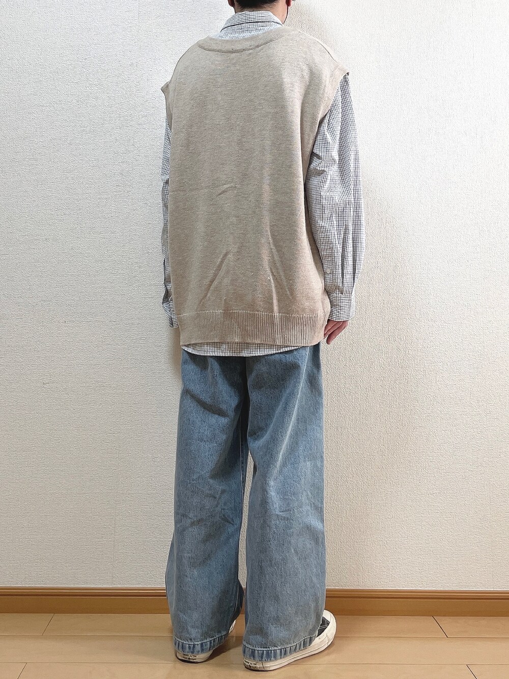 ベージュ系のニット/セーター、ブラック系のシャツ/ブラウス、ブルー系のデニムパンツを着用したメンズの春コーディネートの4枚目の写真