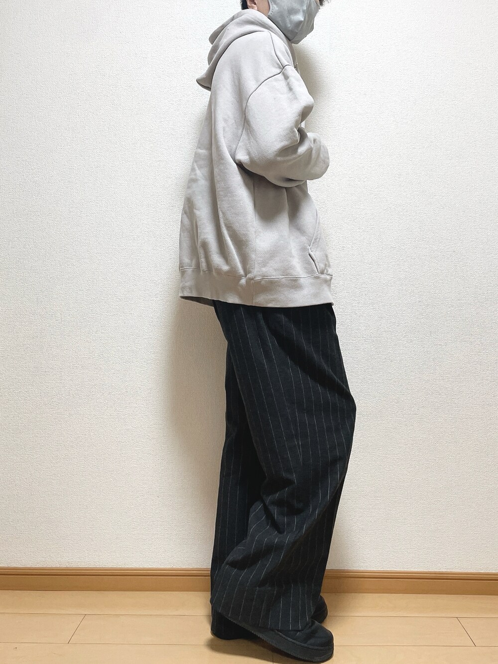 グレー系のパーカー、ブラック系のパンツ、ブラック系のスニーカーを着用したメンズの秋コーディネートの2枚目の写真