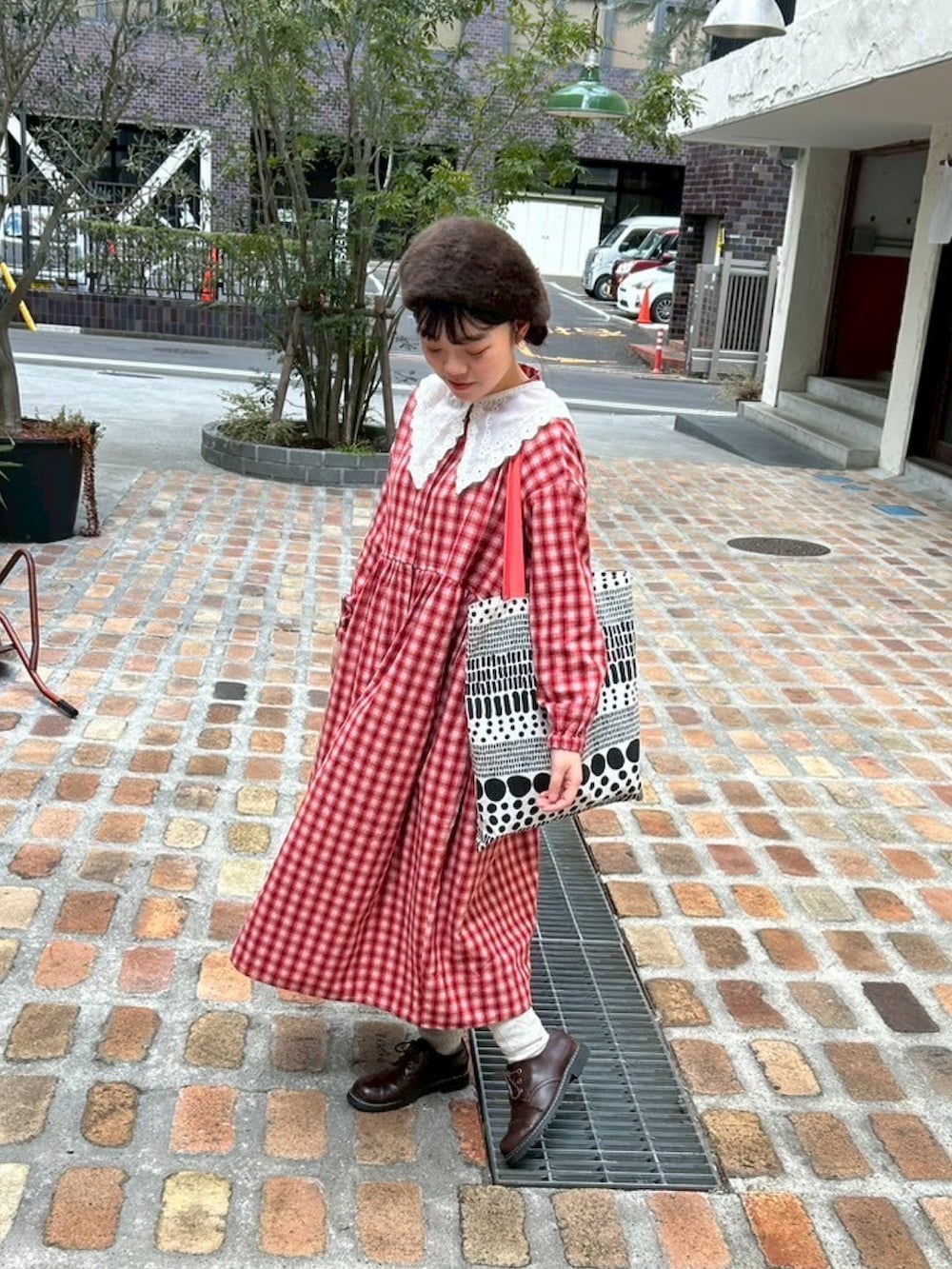 レッド系のワンピース、ブラウン系のその他シューズ、その他のトートバッグを着用したレディースの春コーディネートの2枚目の写真