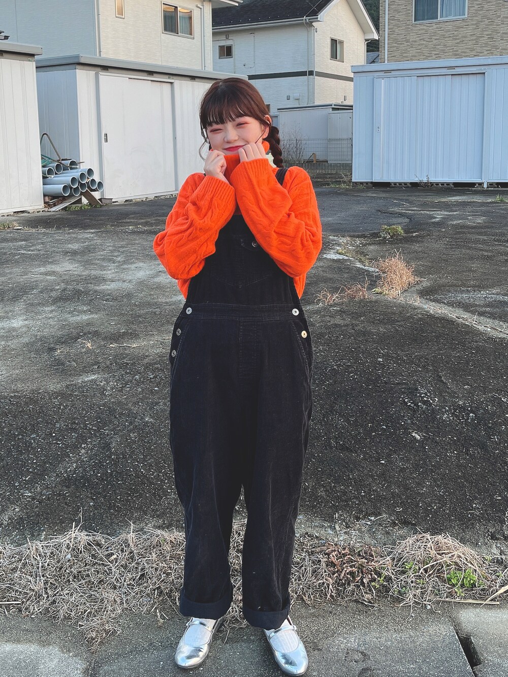 オレンジ系のニット/セーター、シルバー系のバレエシューズ、ブラック系のサロペット/オーバーオールを着用したレディースの冬コーディネートの2枚目の写真